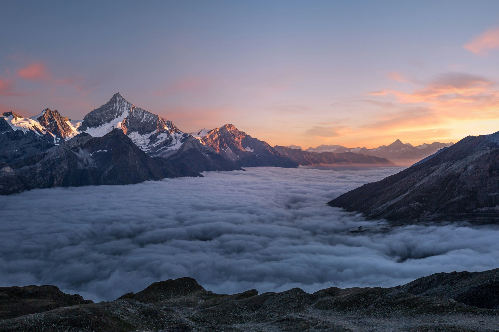 Mountain peaks above a sea of clouds at dawn